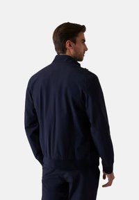 Giubbotto bomber blu navy con colletto alto, zip frontale e polsini e orlo a costine. Texture liscia senza modelli visibili.