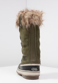 Hohe olivgrüne Winterstiefel mit Kunstpelzkragen, schwarzer Gummisohle und "Sorel"-Branding an Ferse und Seite.