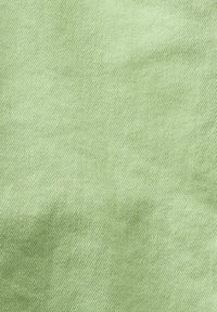 Tissu vert clair à texture nervurée diagonale avec des plis subtils créant des ombres douces.