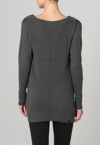 Grijze longsleeve sweater met een brede halslijn, geribbelde manchetten en een naad in het midden. Bevat een subtiele merklabel aan de zoom.