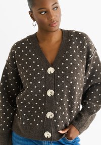 Brown wool cardigan with white polka dots, V-neck, oversized fit, and decorative shell-shaped buttons down the front.