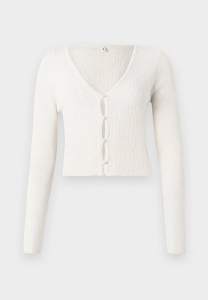 White ribbed cropped cardigan with long sleeves, V-neck, and a front button closure featuring oval openings and bead-like accents.