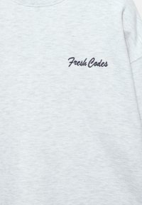 Lysegrå sweatshirt med et struktureret stof, der har et broderet "Fresh Codes" logo i mørkeblå på venstre bryst.