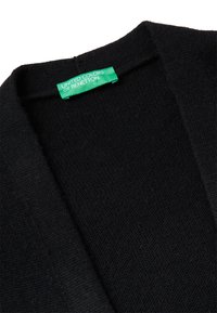 Czarny dziergany kardigan z otwartym przodem, o teksturowanej tkaninie. Metka z napisem "United Colors of Benetton" na białym tle zielonego koloru.