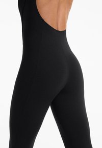Zwarte bodysuit met een aansluitend ontwerp, voorzien van een grote uitsnede op de rug, een gladde textuur en zonder zichtbare hardware of patronen.