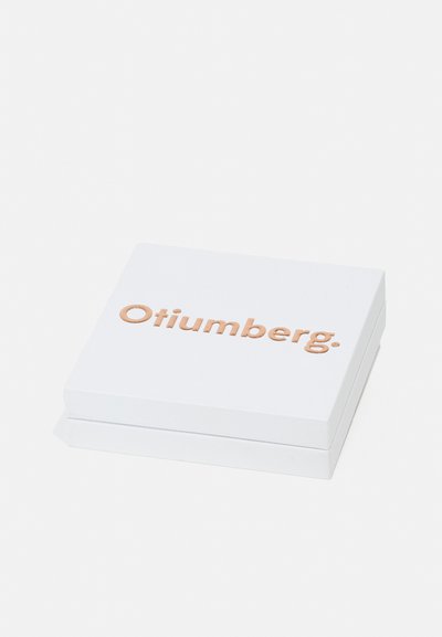 Cutie rectangulară albă cu un finisaj neted, având textul în relief de culoare roz aurie "Otiumberg." pe partea de sus, design minimalist, fără modele suplimentare.