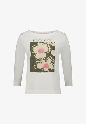 Weißes Langarm-T-Shirt mit floralem Motiv und pinkfarbenen Akzenten auf dunklem Grün, mit dem Schriftzug "smell the blossom".