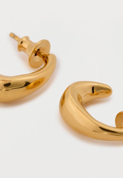 Złote kolczyki o gładkim, zakrzywionym kształcie z błyszczącym wykończeniem. Każdy kolczyk posiada zapięcie na sztyft, co zapewnia pewne noszenie.