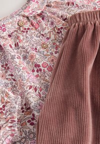 Virágmintás, könnyű szövet rózsaszín, lila és bézs árnyalatokkal, puha, bordázott kordbársonnyal párosítva, tompa rózsaszín színben.