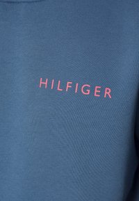 Felpa blu con tessuto testurizzato, caratterizzata da un grande logo rosa "HILFIGER" sul davanti. Collo a giro e vestibilità rilassata.