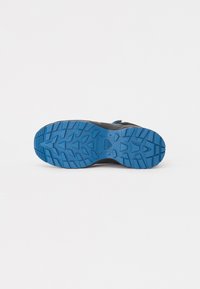 Zapatilla deportiva negra con una suela de goma azul. Presenta un patrón de textura en la suela para mayor agarre y un diseño con cordones para un ajuste seguro.