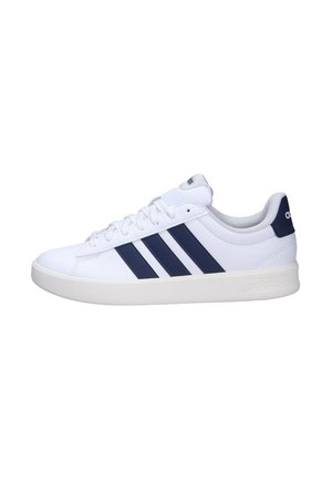 Zapatilla blanca de corte bajo con rayas azul marino de Adidas, suela blanca y cordones, vista desde el lado exterior.