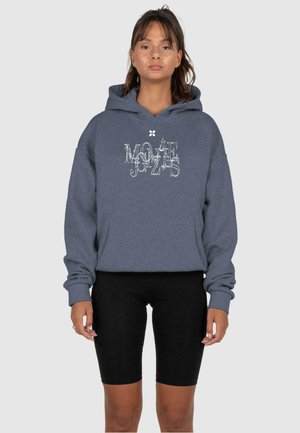 Grå pullover hoodie med et grafisk mønster på fronten, der har en kengurulomme og ribbede manchetter, parret med sorte cykelshorts.