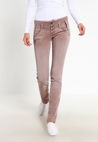 Vaqueros slim-fit de color marrón claro con una textura ligeramente desgastada, que cuentan con múltiples bolsillos, dos botones y detalles de costura a contraste.