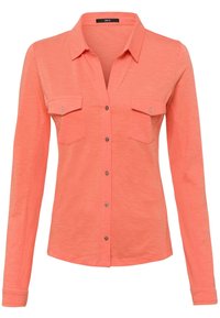 Chemise à manches longues corail avec col, dotée de deux poches avant, d'une fermeture à boutons et d'un tissu doux et texturé. Détails métalliques argentés.