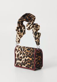 Sac en imprimé léopard avec une forme structurée, en matière textile, accents violets, et une poignée en tissu torsadé pour une texture supplémentaire.