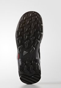Czarna sportowa podeszwa buta z teksturowanym wzorem przyczepności; posiada wyraźny wzór bieżnika i czerwony element z metką; wykonana z gumy i materiałów syntetycznych.