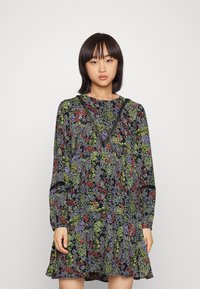 Vestido floral com mangas longas, base preta, apresenta padrões em vermelho, verde e roxo, com acabamento em rendas ao longo da gola, bainha rodada.