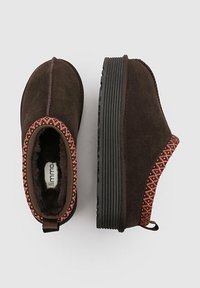 Botas de tobillo de ante marrón con suela negra texturizada. Presentan detalles bordados coloridos en el borde superior y un interior suave.