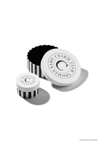 Weiße runde Boxen mit schwarzen Streifen, eine größere mit einem runden Deckel und Logo, eine kleinere, beide mit glatten Oberflächen und glänzender Oberfläche.