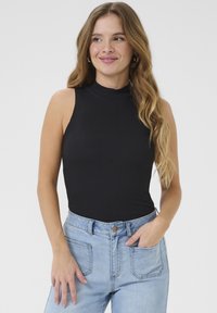 MustHave mustriba särk ilma varrukateta ja kõrge kaelusega, millele on kombineeritud helesinised kõrge vöökohtadega denimist teksad. Sile tekstuur ja keha järgnev disain.
