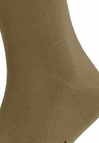 Chaussette marron côtelée avec une texture douce, dotée d'un talon et d'un orteil renforcés. Le design s'étend jusqu'à mi-mollet pour une meilleure protection.