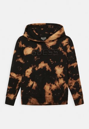 Sweat à capuche tie-dye noir et marron avec une poche kangourou, des poignets côtelés et un logo "GUESS" texturé sur la poitrine.