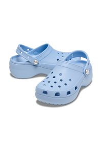 Sabot azzurri chiari realizzati in plastica modellata, dotati di fori di ventilazione, di una fascia posteriore e di suole testurizzate per una migliore aderenza.