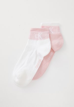To par ankelsokker: en hvit med ribbete rosa mansjett, og en ensfarget lys rosa, begge med diskret merkevare på sidene.