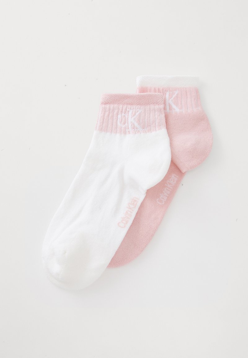 Δύο ζεύγη από κάλτσες μέχρι τον αστράγαλο: μία λευκή με ριγέ ροζ ποδόγυρο και μία ενιαία ανοιχτό ροζ, και οι δύο με διακριτική σήμανση στα πλάγια.
