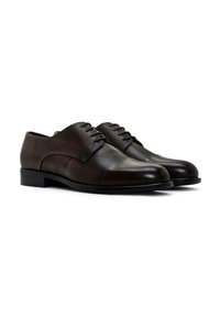 Zapatos de dress de cuero marrón con un acabado texturizado, punta redondeada y dos ojales para cordones. Presenta una puntera lisa y un tacón bajo y plano.
