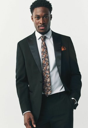 Black tuxedo with satin lapels, white shirt, floral tie in brown and orange tones, and an orange pocket square. Tailored fit.