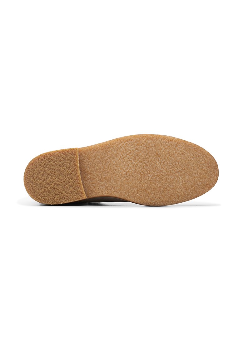 Beige Gummisohle mit strukturierter Oberfläche und abgerundetem Rand. Verfügt über einen festen braunen Abschnitt an der Rückseite und einen glatten vorderen Bereich.