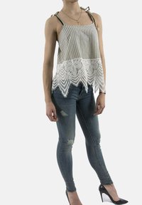 Top senza maniche a righe con orlo in pizzo bianco, spalline regolabili, abbinato a jeans skinny strappati e tacchi alti neri.