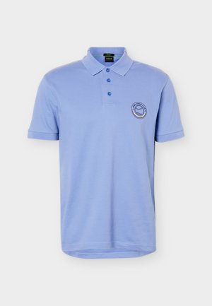 Polo de manga corta de color azul claro con tres botones y un pequeño logo redondo con una pelota de tenis en el pecho izquierdo.