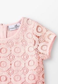 Rosa spetklänning för flickor med cirkulära blommönster, korta ärmar och rund halsringning, med en "glada flickor"-etikett inuti kragen.