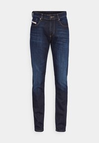 Jean en denim bleu foncé avec une coupe slim, présentant des coutures orange contrastantes, une fermeture à bouton classique et cinq poches.