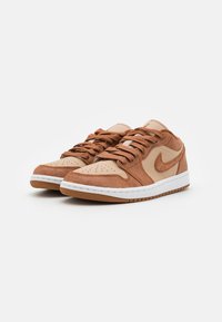 Baskets en suède et cuir marron avec une boîte à orteils perforée, un laçage à l'avant et une semelle intermédiaire blanche. Présente un swoosh Nike beige et une semelle en caoutchouc.