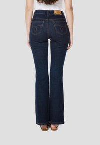 Donkere blauwe denim jeans met uitlopende pijpen en een hoge taille, voorzien van twee achterzakken, subtiele stikdetails en een bruin leren logoplaatje.