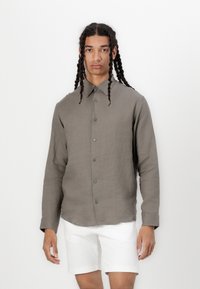 Camisa de lino ligera de color gris marrón con botones en la parte delantera, cuello puntiagudo y mangas largas. Textura suave, con botones verdes.