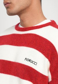 Rot und weiß gestreifter Pullover aus weichem Material mit Rundhalsausschnitt. Verfügt über ein gesticktes "Fiorucci"-Logo auf der Brust.