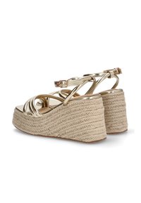 Sandalias de cuña doradas con tiras trenzadas de yute, que cuentan con una delgada correa en el tobillo y tiras frontales redondeadas. Superficie texturizada.