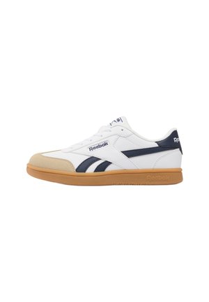 Sneaker bianca Reebok con punta beige, strisce blu navy e suola in gomma, vista di profilo.