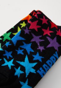 Black socks featuring a pattern of colorful stars in red, green, blue, and purple, with the word "HAPPY" in bold blue text.