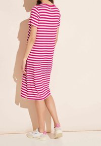 Różowa i biała sukienka w paski, z krótkim rękawem, o długości do kolan z rozcięciami po bokach. W połączeniu z białymi trampkami z różowymi akcentami.