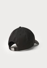 Căciulă neagră dintr-un material neted, cu o coroană rotundă și o margine curbată. Dispune de un accent cu logo metalic pe cureaua ajustabilă de la spate.