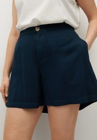 Pantaloni corti blu navy realizzati in tessuto morbido, con chiusura frontale a bottone, tasche laterali e una vestibilità ampia e fluida.