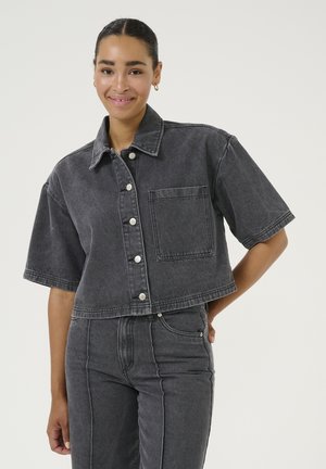 Cropped black denim jacket with short sleeves, silver snap buttons, and a single chest pocket. Textured fabric with a faded appearance.
