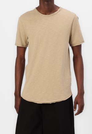 Beige kortærmet t-shirt med en let struktureret stof, rund halsudskæring og rå kantdetaljer ved ærmer og nederste kant.