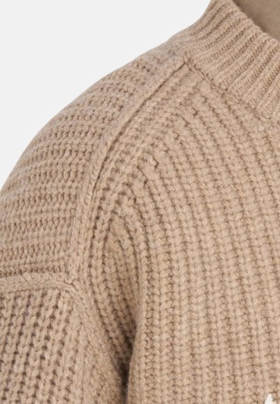 Pull en tricot beige avec un motif de point texturé, doté d'un col côtel é et de détails de couture sur l'épaule.
